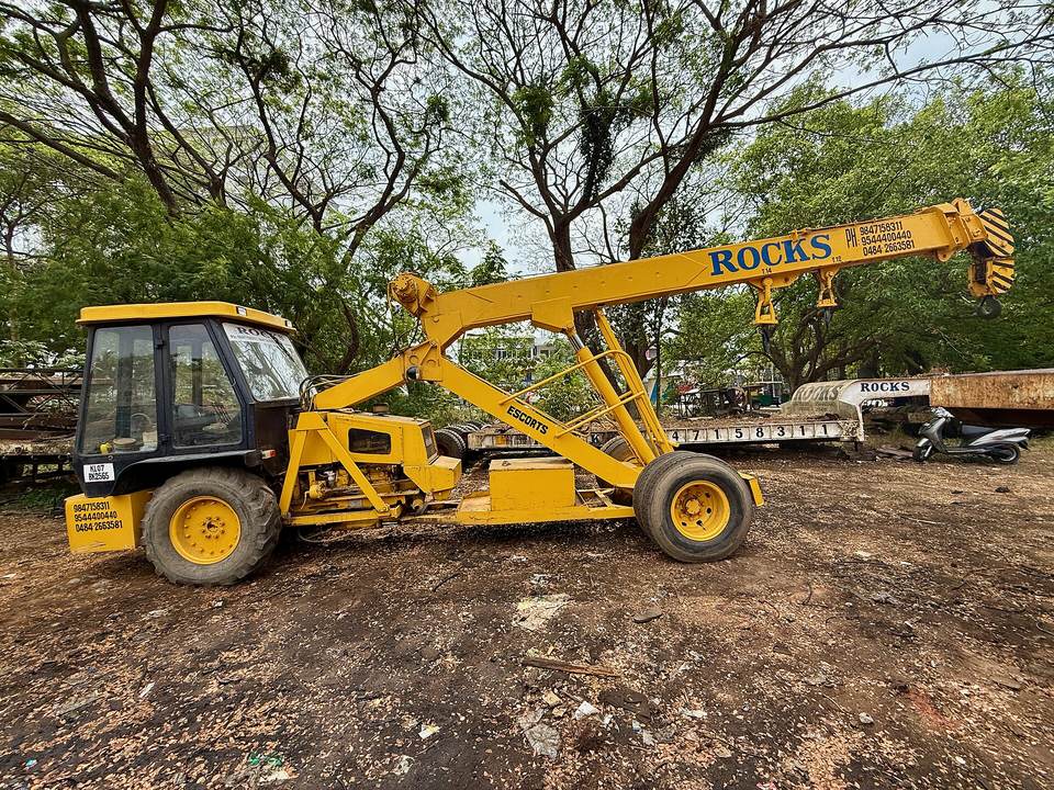 Yellow Escorts Hydra pick-and-carry crane with its boom raised, parked on a site
